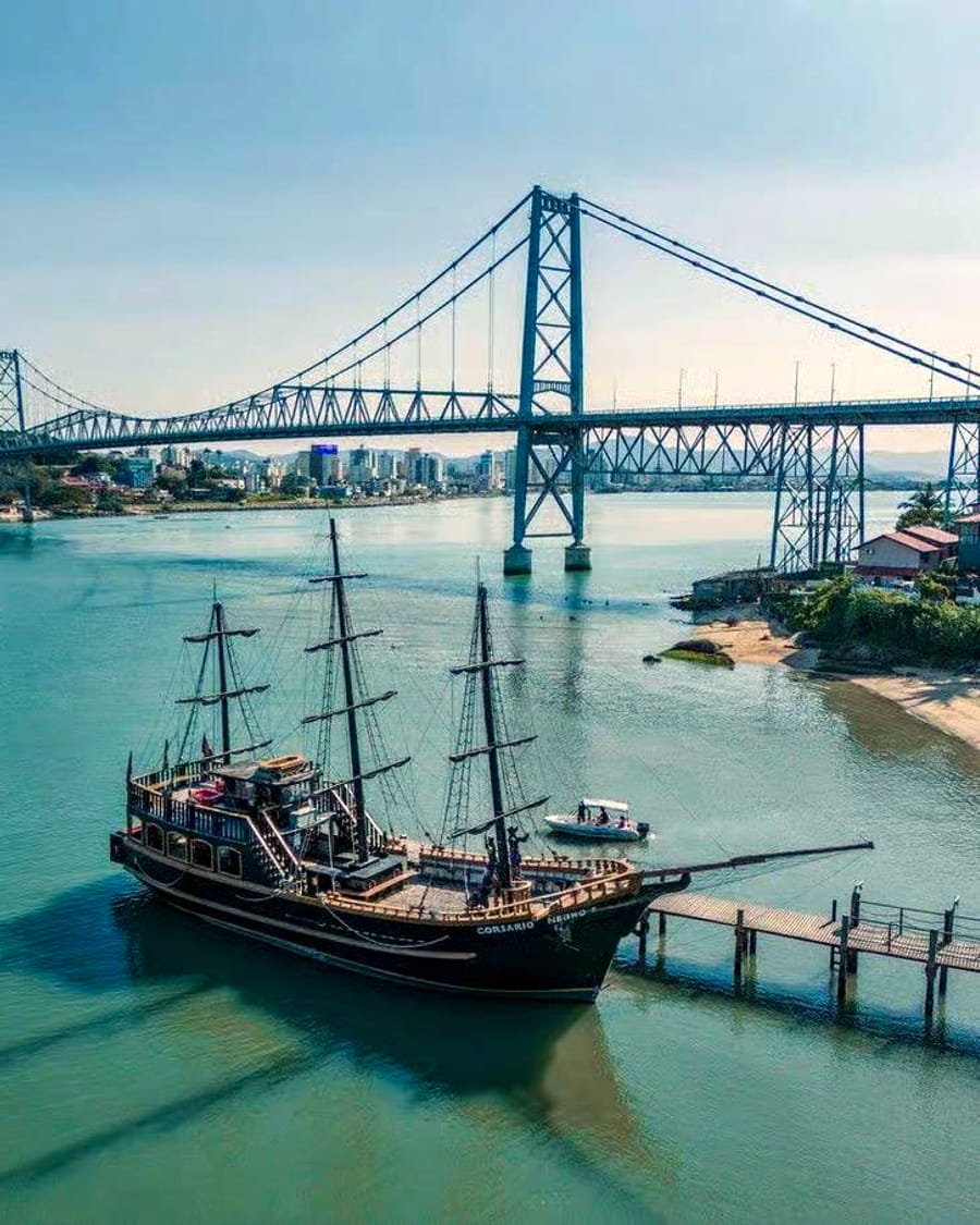 The Corsário Negro tall ship moored in front of the Hercílio Luz bridge