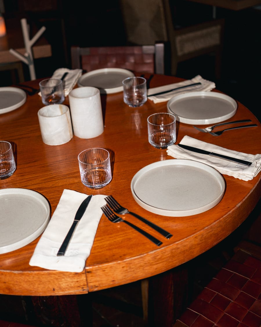 Wooden table set with plates, glasses and cutlery